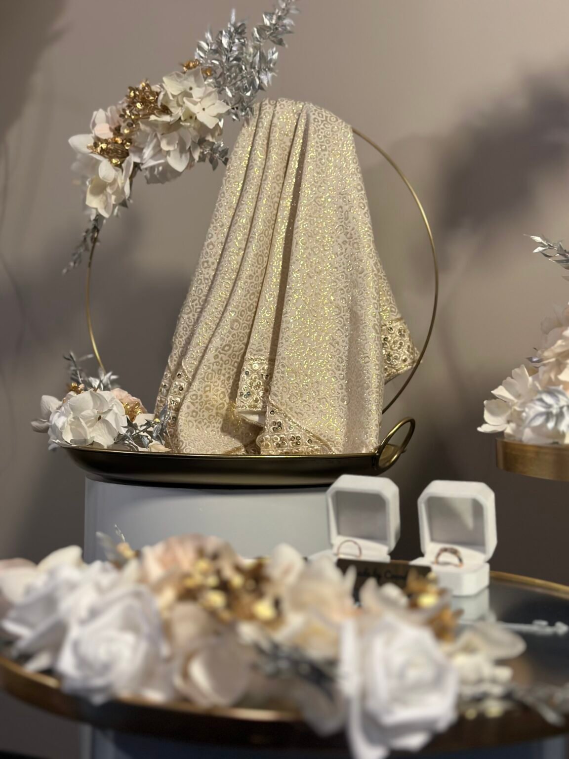 Gedrapeerde goudkleurige doek over een gouden ring met bloemwerk